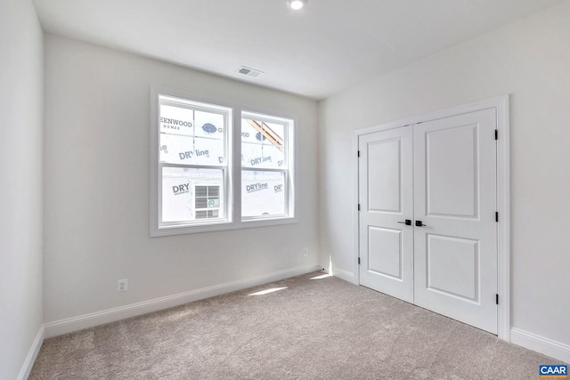 unfurnished bedroom with light carpet and a closet