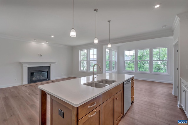 kitchen featuring a kitchen island with sink, crown molding, sink, light hardwood / wood-style flooring, and stainless steel dishwasher