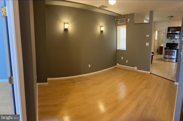 interior space with a baseboard radiator, light hardwood / wood-style flooring, and an AC wall unit