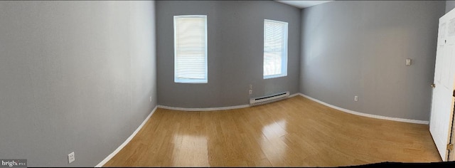 spare room with baseboard heating and wood-type flooring