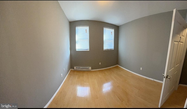 unfurnished room featuring hardwood / wood-style flooring, vaulted ceiling, and a baseboard heating unit