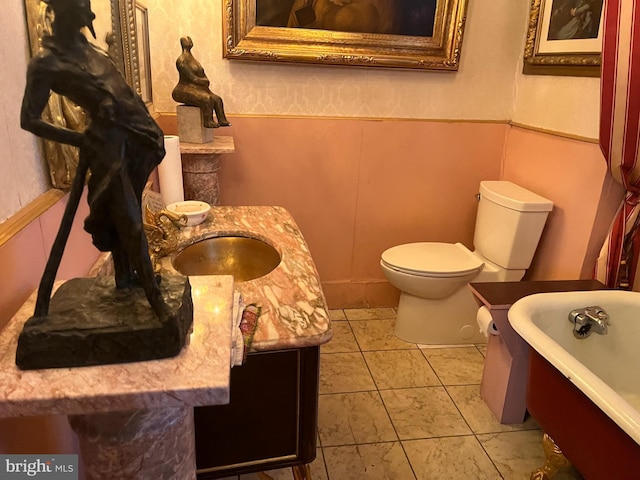 bathroom featuring a tub to relax in, toilet, and sink