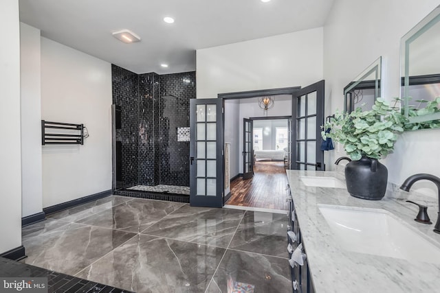 bathroom featuring hardwood / wood-style flooring, vanity, tiled shower, and french doors