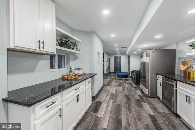 kitchen with dark stone countertops, white cabinetry, dark wood-type flooring, and appliances with stainless steel finishes