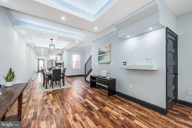 dining area featuring a raised ceiling, dark hardwood / wood-style flooring, an inviting chandelier, and ornamental molding