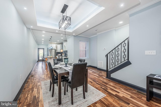 dining area with hardwood / wood-style floors, a tray ceiling, ornamental molding, and a notable chandelier