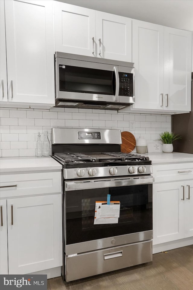 kitchen with backsplash, white cabinetry, and stainless steel appliances