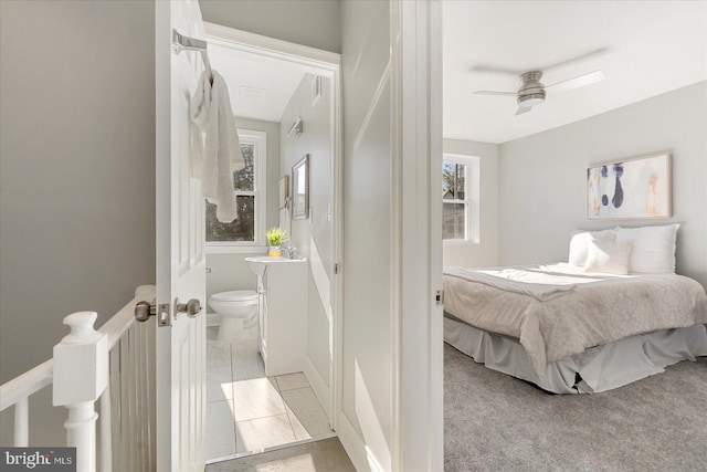 carpeted bedroom with ensuite bath, ceiling fan, and sink