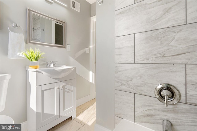 bathroom with tile patterned floors, vanity, toilet, and tiled shower