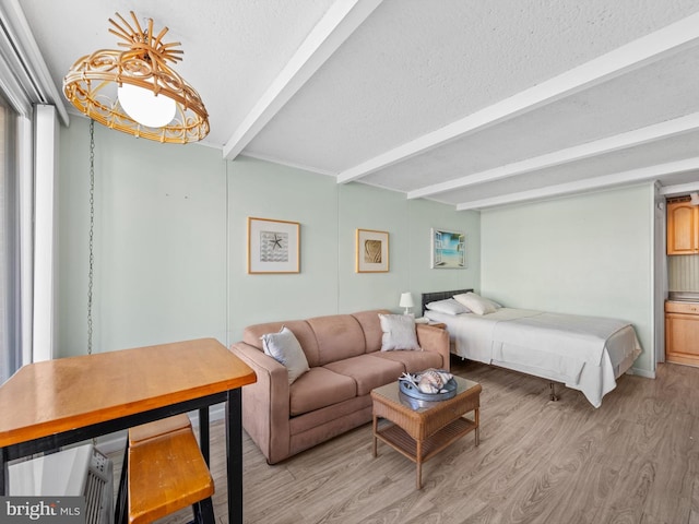 bedroom featuring beam ceiling, light hardwood / wood-style flooring, and a textured ceiling