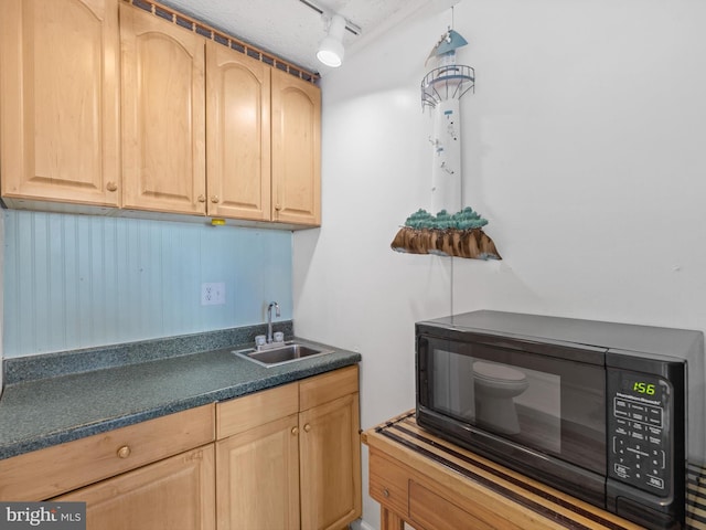 kitchen with rail lighting, sink, light brown cabinetry, and a textured ceiling