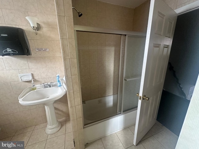 bathroom featuring tasteful backsplash, tile patterned floors, tile walls, and bath / shower combo with glass door