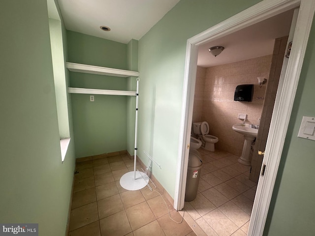 bathroom featuring tile patterned floors, toilet, tile walls, and a bidet