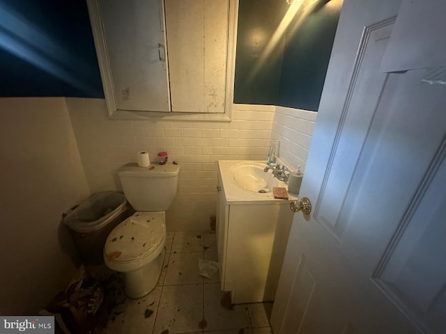 bathroom with tile patterned flooring, vanity, toilet, and tile walls