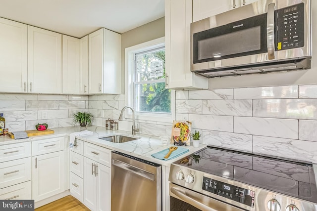 kitchen with white cabinets, appliances with stainless steel finishes, decorative backsplash, and sink