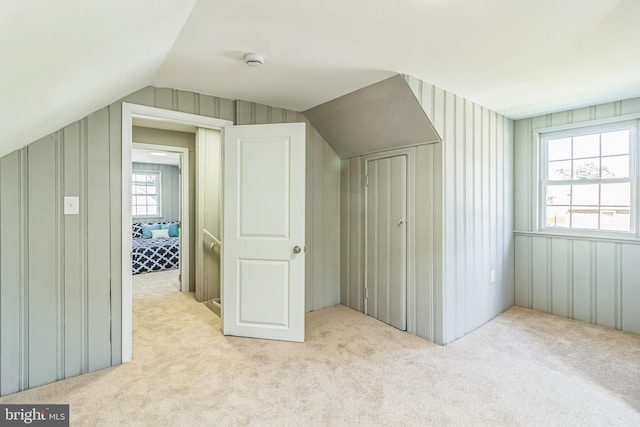 bonus room with plenty of natural light, light colored carpet, and lofted ceiling