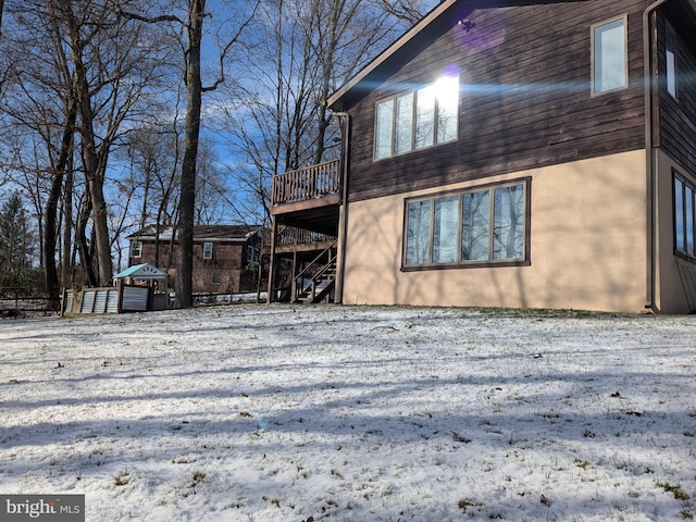 snow covered property with a wooden deck and stairs