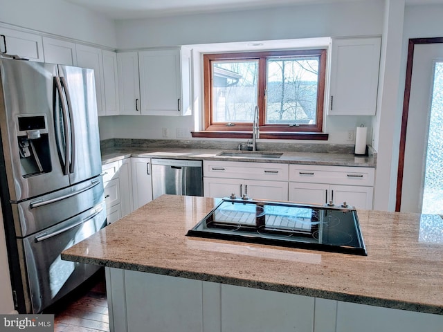 kitchen with white cabinets, light stone counters, appliances with stainless steel finishes, and a sink