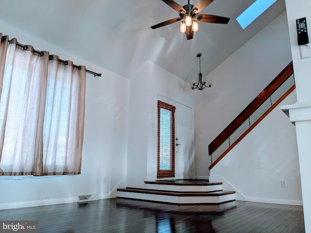 entrance foyer with ceiling fan with notable chandelier, hardwood / wood-style flooring, high vaulted ceiling, and a skylight