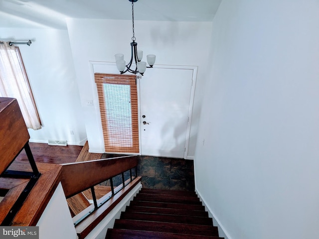 staircase with visible vents, wood finished floors, and a chandelier