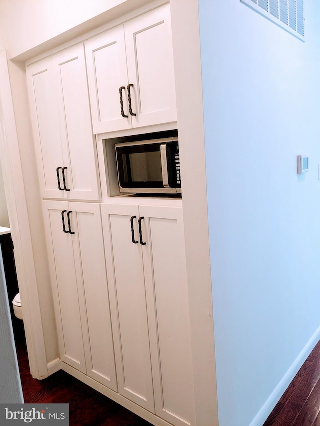 interior details featuring dark hardwood / wood-style floors and white cabinetry