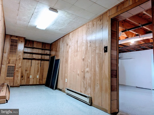 basement featuring a baseboard radiator and wooden walls