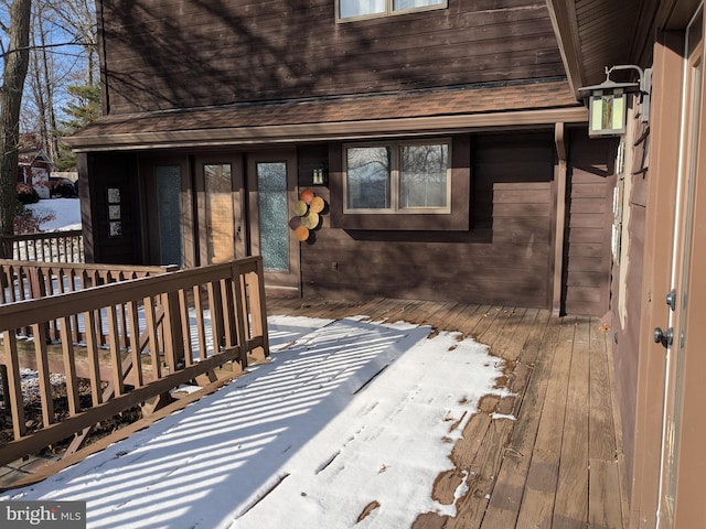 snow covered property entrance with a deck