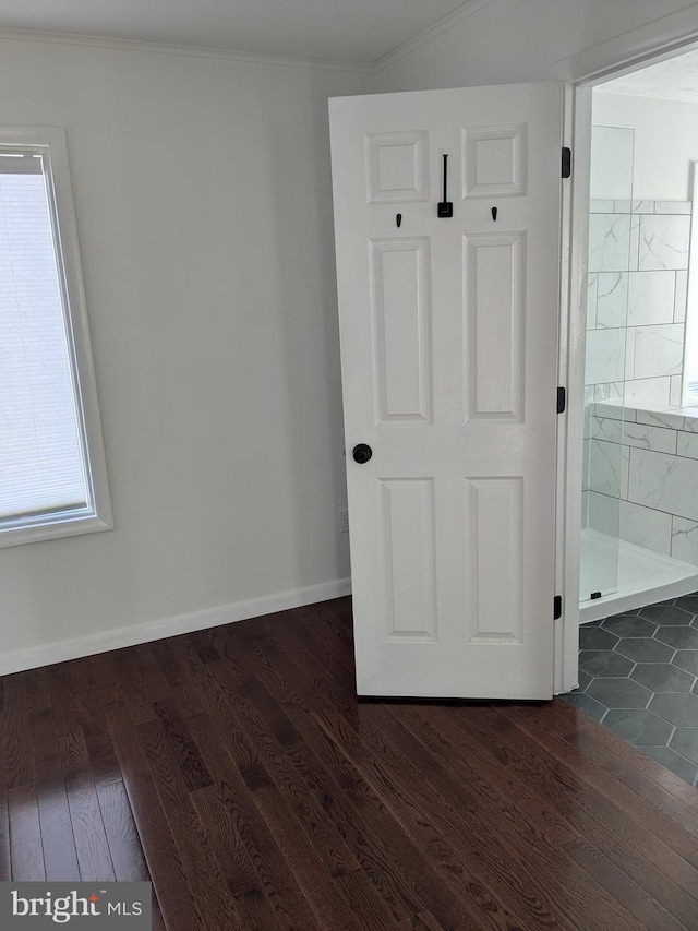 unfurnished bedroom featuring ornamental molding, connected bathroom, baseboards, and dark wood-style flooring