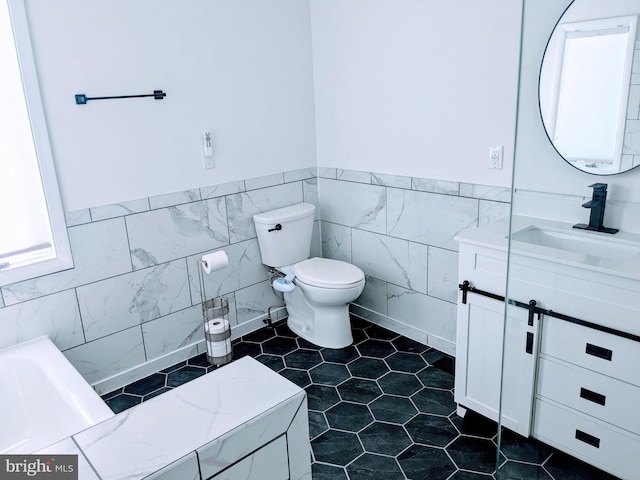 bathroom featuring vanity, toilet, and tile walls