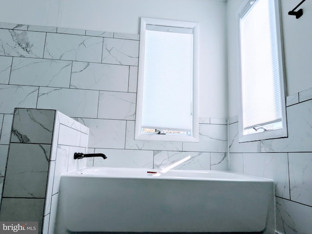 full bathroom with a garden tub, a healthy amount of sunlight, and tile walls