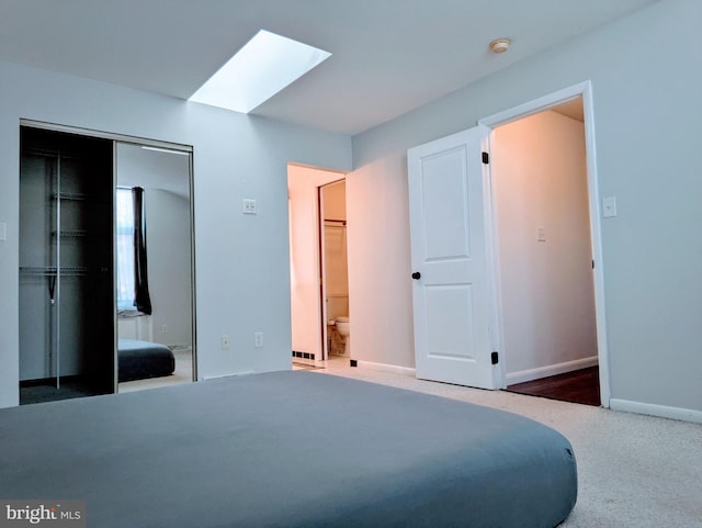 carpeted bedroom with a skylight, ensuite bath, and a closet