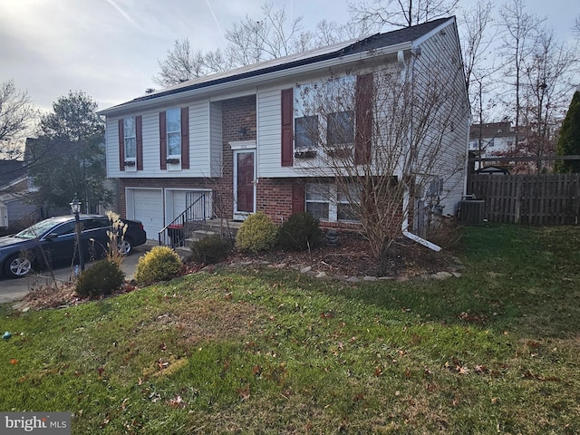 raised ranch featuring a garage, a front yard, and central AC