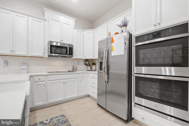 kitchen featuring backsplash, white cabinets, light hardwood / wood-style floors, and appliances with stainless steel finishes