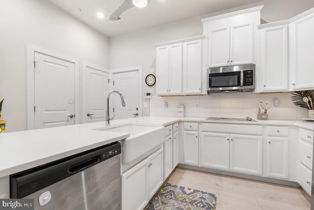 kitchen with white cabinets, backsplash, sink, and stainless steel appliances