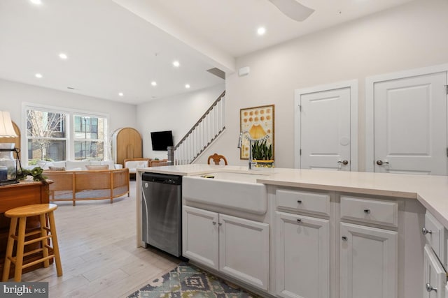 kitchen featuring white cabinetry, sink, dishwasher, ceiling fan, and light wood-type flooring