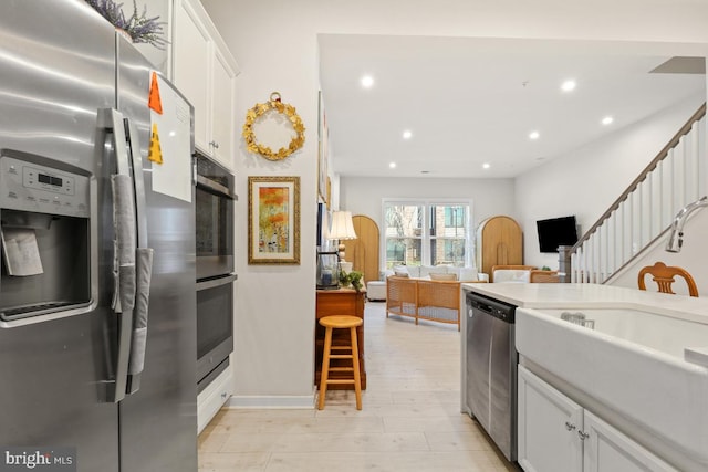 kitchen with white cabinets, appliances with stainless steel finishes, light wood-type flooring, and sink