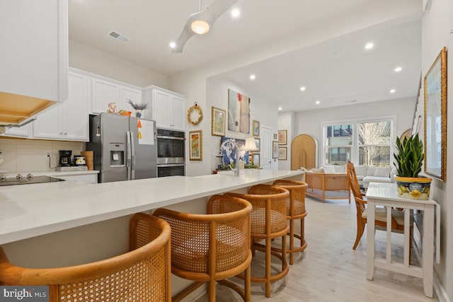 kitchen featuring white cabinets, kitchen peninsula, a breakfast bar area, and appliances with stainless steel finishes