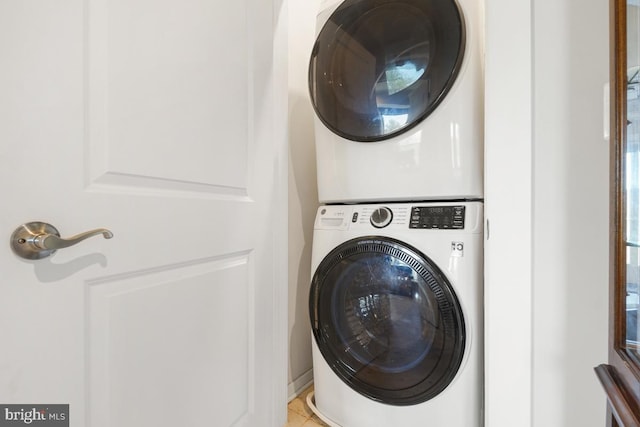 clothes washing area featuring light tile patterned floors and stacked washer and clothes dryer