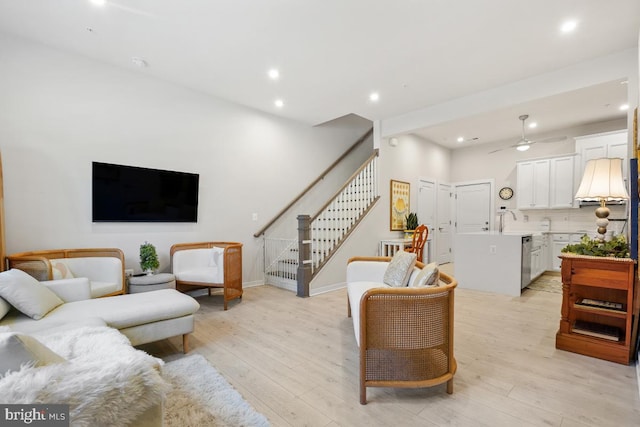 living room with ceiling fan, light hardwood / wood-style floors, and sink