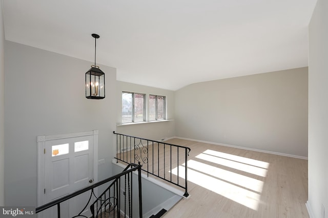 stairs with wood-type flooring, an inviting chandelier, and vaulted ceiling