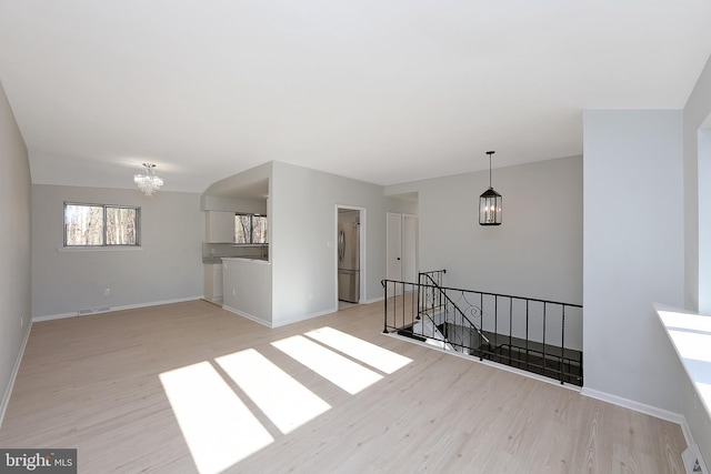 spare room with an inviting chandelier and light hardwood / wood-style flooring