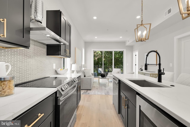 kitchen with pendant lighting, sink, light hardwood / wood-style flooring, light stone countertops, and appliances with stainless steel finishes