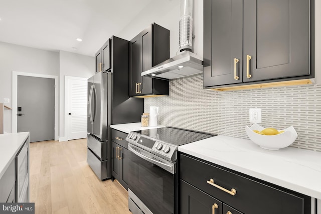 kitchen featuring wall chimney exhaust hood, light stone counters, decorative backsplash, appliances with stainless steel finishes, and light wood-type flooring