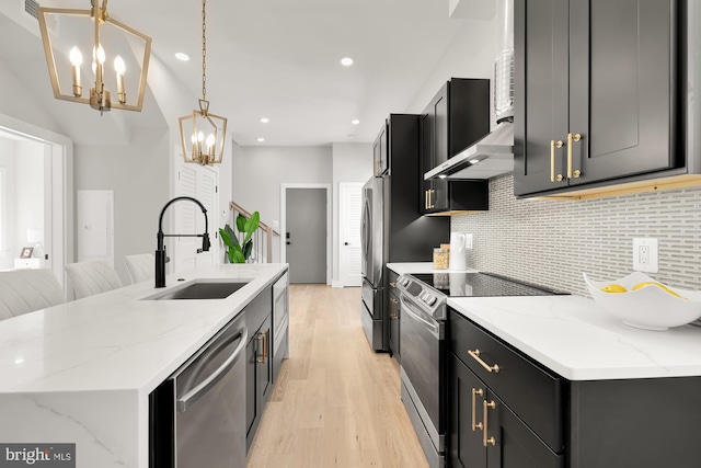 kitchen featuring pendant lighting, sink, light stone countertops, appliances with stainless steel finishes, and light hardwood / wood-style floors