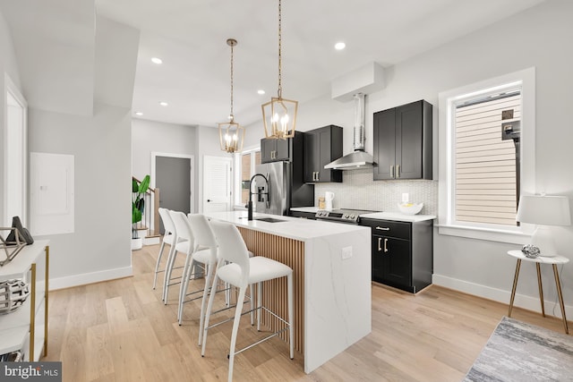 kitchen with appliances with stainless steel finishes, light hardwood / wood-style flooring, a kitchen island with sink, and a breakfast bar area