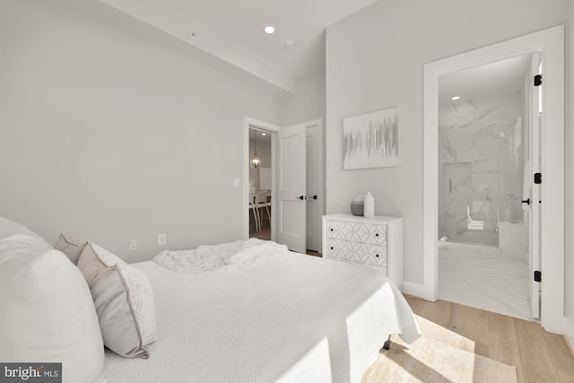 bedroom featuring ensuite bath and light wood-type flooring