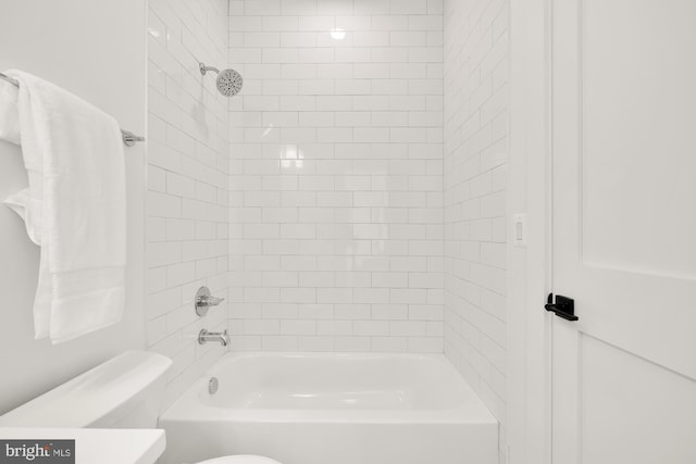 bathroom featuring tiled shower / bath combo and toilet