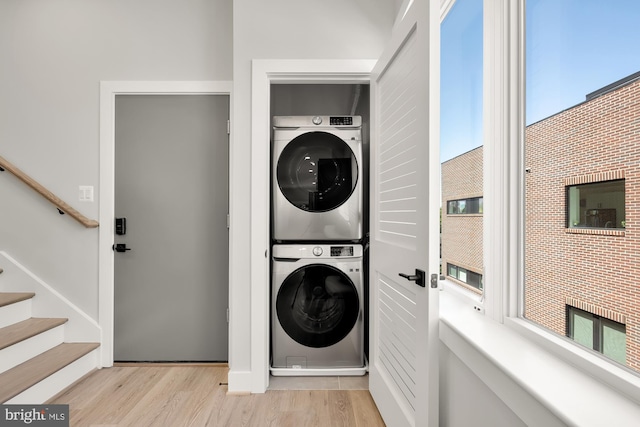 washroom with light hardwood / wood-style flooring and stacked washer / drying machine