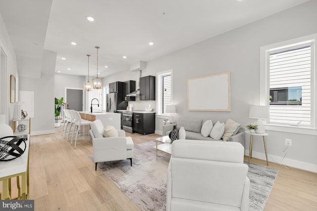 living room with a chandelier, sink, and light hardwood / wood-style floors