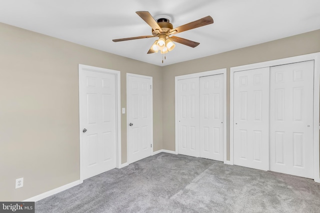 unfurnished bedroom with ceiling fan, light carpet, and multiple closets